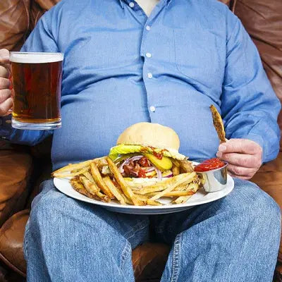 Unhealthy meal on lap with Health-Enhancing Herbal Tea featuring Hovenia Dulcis Thunb and Tangerine Peel