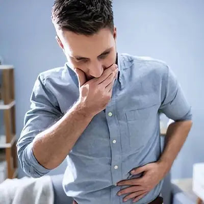 Nauseous man in blue shirt drinking herbal tea during golden hour for irregular diet relief