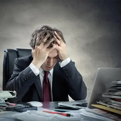Stressed businessman with hands on head enjoying Sleep Tea made with Pina Date Seed herbal tea for better sleep quality