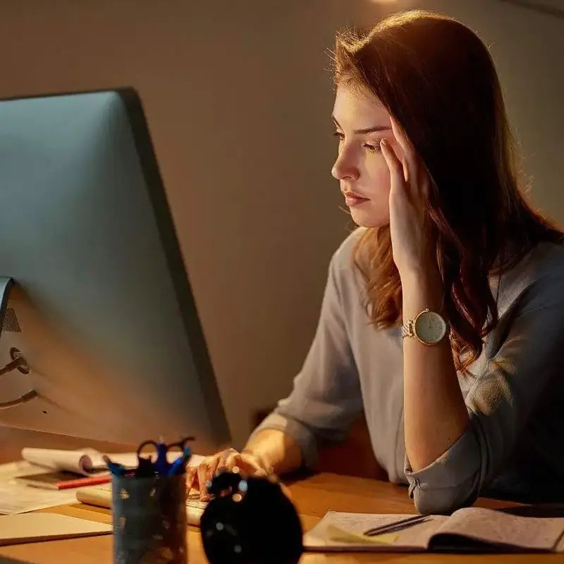Woman working at a computer during golden hour with Lotus Leaf Tea promoting intestinal motility