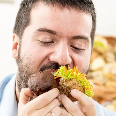 Man enjoying two muffins with Stomach Tea herbal tea during golden hour for irregular diet health