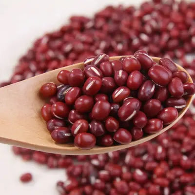 Red adzuki beans on wooden spoon in herb tea for detox supporting detoxification processes