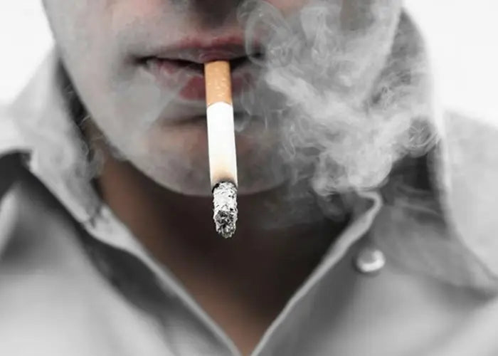 Lit cigarette in mouth with Lung Tea featuring Siraitia Grosvenorii and Boat-Fruited Sterculia for cough relief