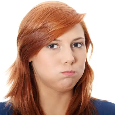 Red-haired woman with puffed cheeks enjoying herbal tea during golden hour for irregular diet health