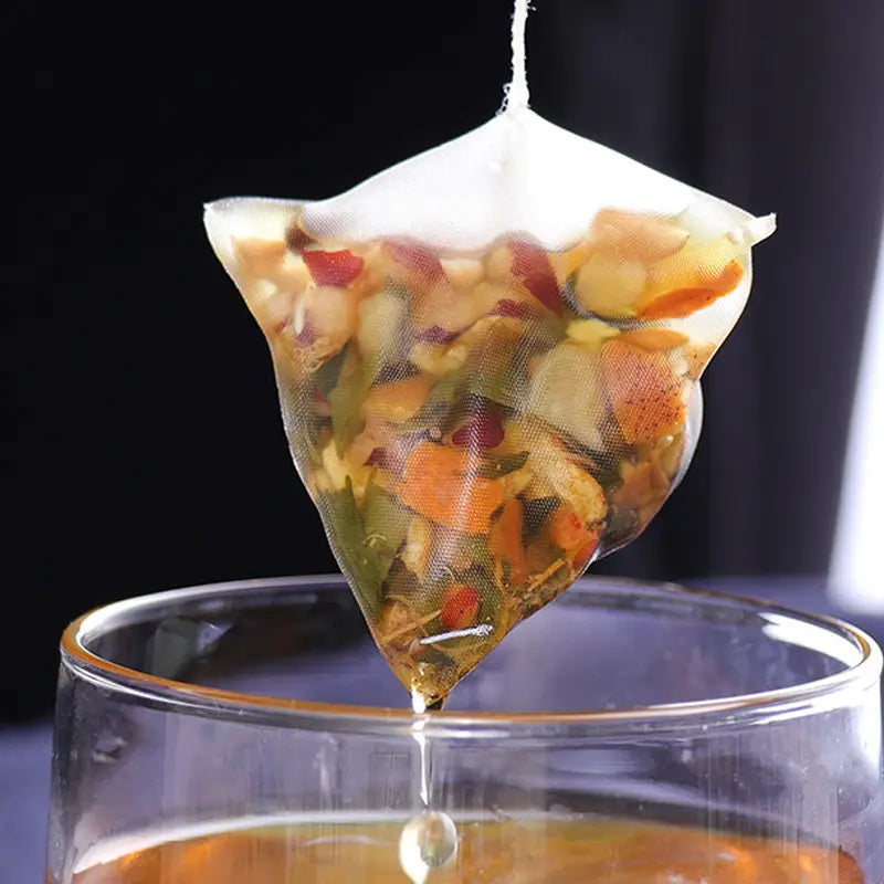 Herbal tea triangular bag dripping into glass during golden hour for irregular diet support
