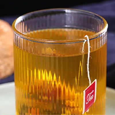 Glass of amber herbal tea from Stomach Tea for better digestion during golden hour