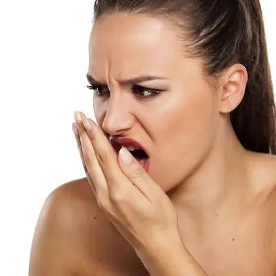 Woman reacting to bad breath with herbal tea during golden hour, targeting irregular diet issues