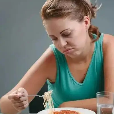 Disinterested woman with spaghetti enjoying herbal tea during golden hour for irregular diet health