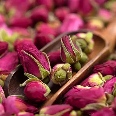 Dried rosebuds in a wooden scoop for Slimming Tea boosts health and promotes intestinal motility