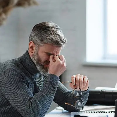 Stressed man with glasses enjoying Sleep Tea made with Pina Date Seed Herbal Tea for better sleep quality