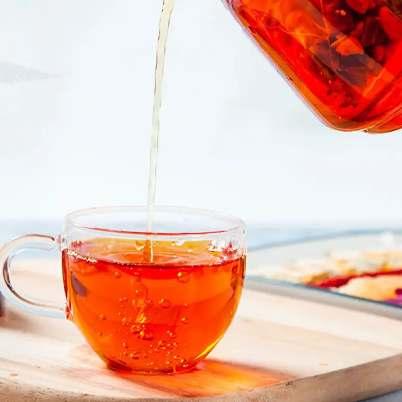 Glass teacup being filled with Dysmenorrhea Tea, herbal tea for cramps alleviating menstrual pain