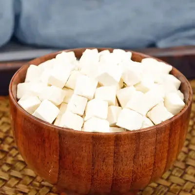Wooden bowl with cubed tofu paired with herbal tea affecting health during golden hour