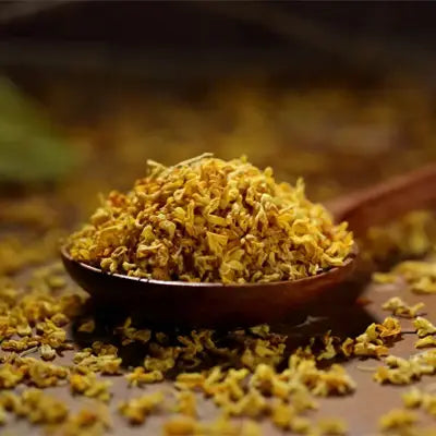 Dried yellow flowers in a wooden spoon for Liver Detox Herbal Tea with Chrysanthemum Cassia Seed
